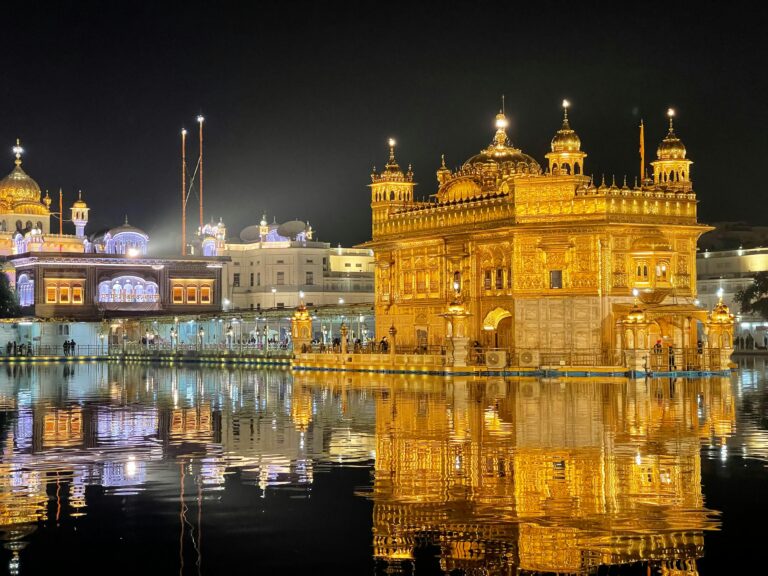 Illuminated night view of the Golden Temple in Amritsar, India, with a stunning water reflection.