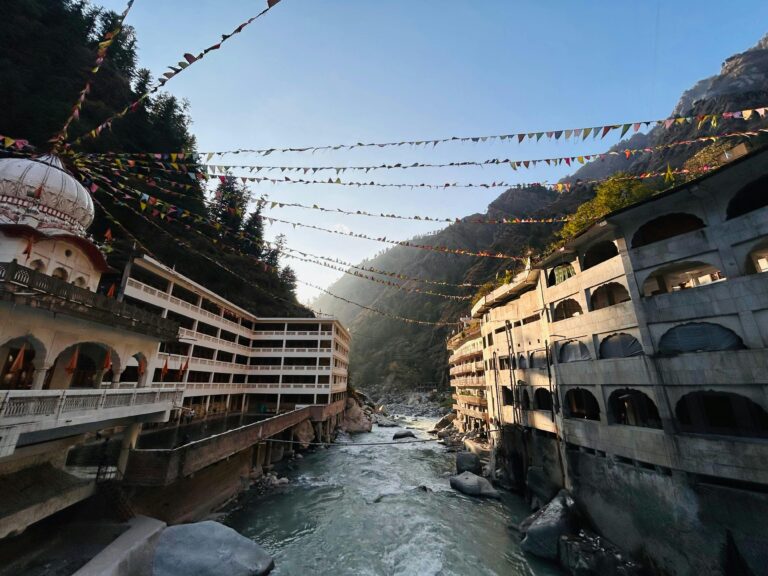 River flowing through Kasol, Himachal Pradesh, framed by mountains and prayer flags.